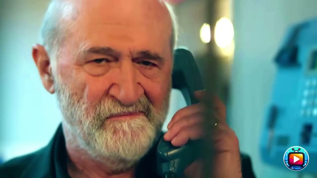 Primo piano di un uomo anziano, calvo e con la barba bianca, che tiene accostata all'orecchio la cornetta di un telefono a muro